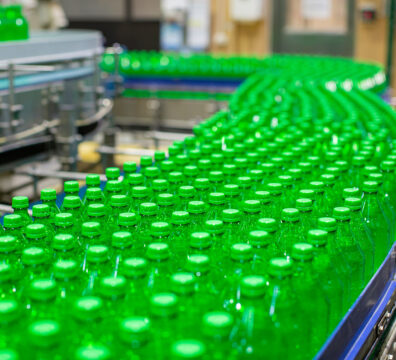 Beverage factory interior. Conveyor flowing with bottles green for water.