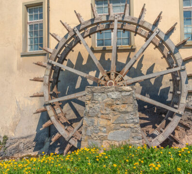 Working watermill wheel in front of an old house.